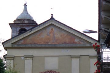 Chiesa parrocchiale con campanile a cupola e portale con tetto in tegole a protezione della porta di ingresso