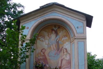 Cappelletta votiva con affresco centrale che raffigura Gesù Bambino in trionfo con la croce, in basso San Rocco a sinistra e Santa Lucia a destra, all'esterno dipinta in azzurro.