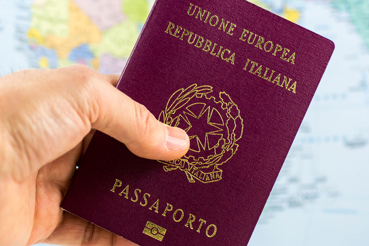 Una mano mostra un passaporto italiano.