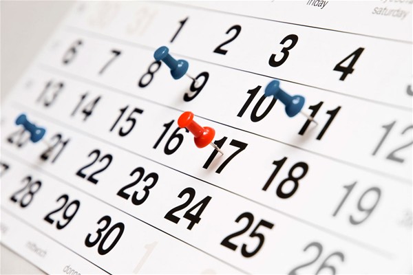 Un calendario mensile con alcuni giorni segnati da 3 spilli blu ed uno spillo rosso.