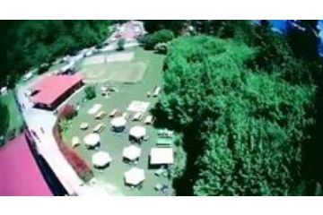 Edificio con ampio spazio esterno e campo di pallavolo su sabbia con tavoli e sedie.